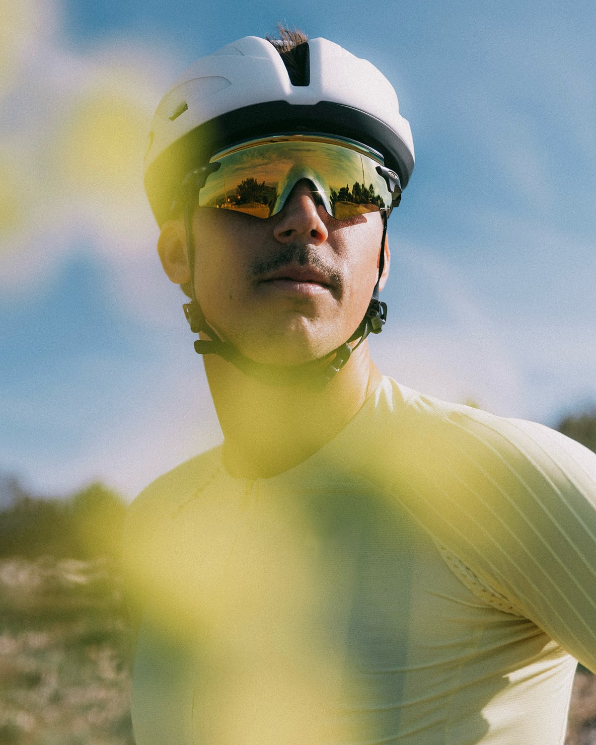 Portrait d'un cycliste en maillot jaune, lunettes de soleil, sous un ciel bleu